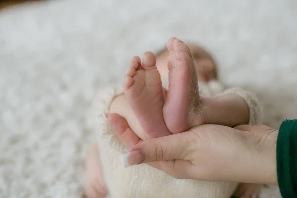 Dłonie Mamy Trzymają Słodkie Nóżki Dziecka Które Leży Wiklinowym Koszu — Zdjęcie stockowe