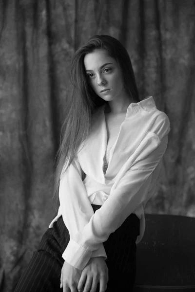 白いシャツに黒い長髪の素敵な若い女の子のモデルと黒のパンツは 織物の背景にスタジオでポーズをとっています 美とファッション — ストック写真