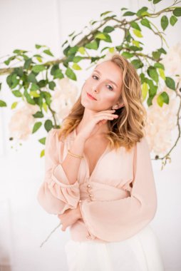 Sarışın, kıvırcık saçlı, zarif sarı şifon bluzlu, beyaz orkideli güzel makyajlı çekici bir genç kız.