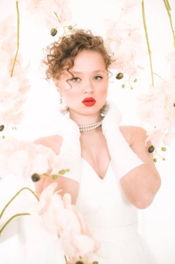 Beyaz orkideli, hafif bahar stüdyosunda beyaz elbiseli çekici bir gelin. Güzellik ve Moda