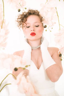 Beyaz orkideli, hafif bahar stüdyosunda beyaz elbiseli çekici bir gelin. Güzellik ve Moda