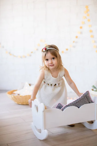 Μικρό Χαριτωμένο Κορίτσι Ένα Λευκό Φόρεμα Παίζει Ένα Κρεβάτι Κούκλα — Φωτογραφία Αρχείου