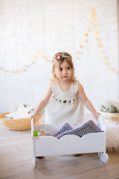 Μικρό Χαριτωμένο Κορίτσι Ένα Λευκό Φόρεμα Παίζει Ένα Κρεβάτι Κούκλα — Φωτογραφία Αρχείου
