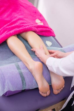 Kız masaj terapisti masaj masasında masaj yapan bir kıza bacak masajı yapıyor. Spa tedavileri. Sağlık ve güzellik