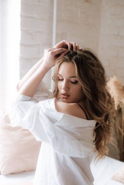 Yatak odasında uzun kıvırcık sarı saçlı, güzel dantelli geceliği ve beyaz gömleği olan güzel bir genç kız..