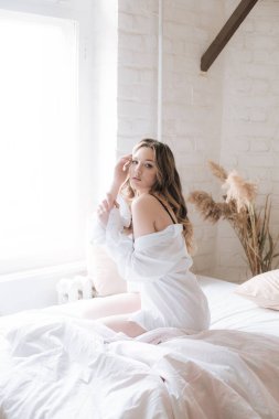 Yatak odasında uzun kıvırcık sarı saçlı, güzel dantelli geceliği ve beyaz gömleği olan güzel bir genç kız..