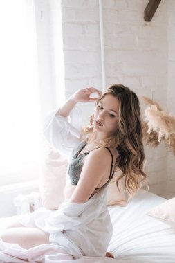 Yatak odasında uzun kıvırcık sarı saçlı, güzel dantelli geceliği ve beyaz gömleği olan güzel bir genç kız..