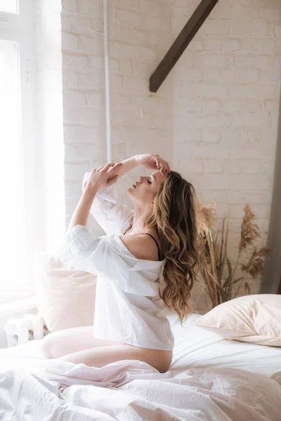 可爱的小女孩 早上在卧室里 一头长长的卷曲的金发 穿着漂亮的花边睡衣和白衬衫 — 图库照片