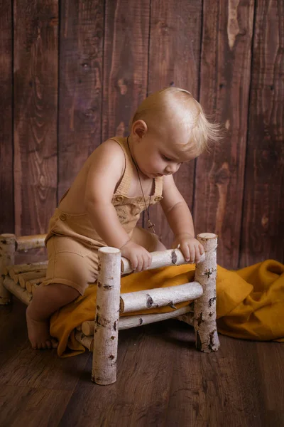 금발의 귀여운 아기는 어두운 배경에 자작나무 가지로 침대를 가지고 것이다 — 스톡 사진