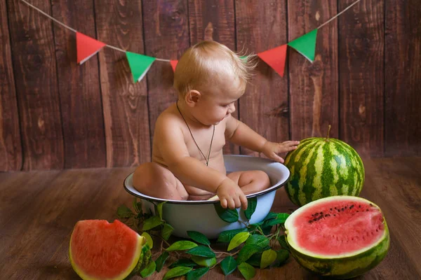 금발의 귀여운 아기가 어두운 배경에 수박을 앉아서 물장구를 아이들 — 스톡 사진