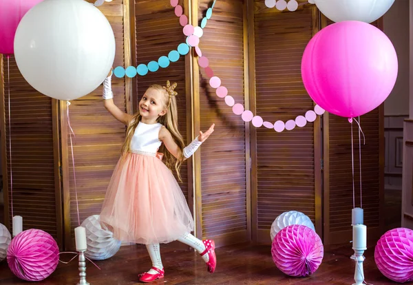 ピンクのドレスに金髪のかわいい女の子と大きな明るい風船やガーランドとプリンセスクラウン 子供の休日 子供用の装飾品 — ストック写真