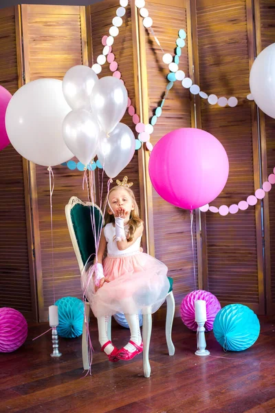 一个可爱的小女孩 金发碧眼 穿着粉红的衣服 头戴公主王冠 戴着大大的明亮的气球和花环 儿童节 儿童的装饰 — 图库照片