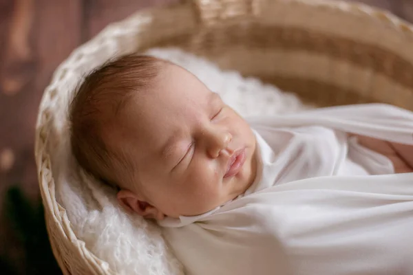 木製の床に針と綿の枝で飾られたウィッカーバスケットの白い毛布の中に小さなかわいい赤ちゃん 幸せな母親 — ストック写真
