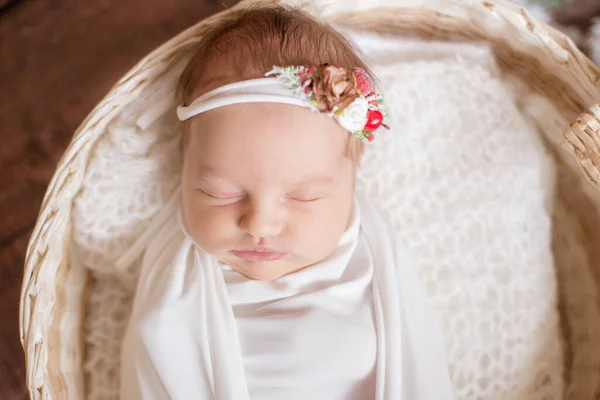 小可爱的婴儿 头戴白色毯子 头戴鲜花 头戴柳条篮 用针枝和棉花装饰在木地板上 母性快乐 — 图库照片