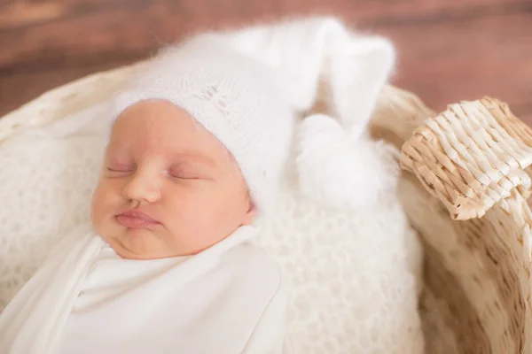 穿着白色毛毯的可爱小宝宝 戴着白色针织帽子 头戴柳条篮 用针枝和棉花装饰在木制地板上 母性快乐 — 图库照片