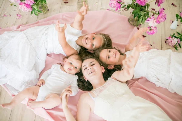 かわいい子供たち 白いドレスの弟と姉がピンクの牡丹の明るい春のスタジオの床に一緒に横たわっています 幸せな家族だ 幸せな子供時代 — ストック写真