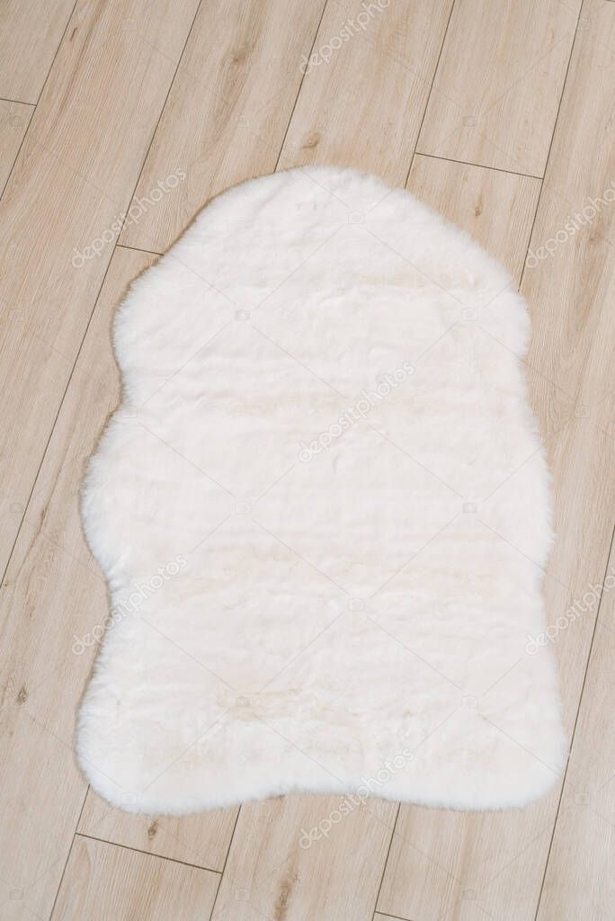 Small interior rug made of faux rabbit fur in white color. Interior decoration details.
