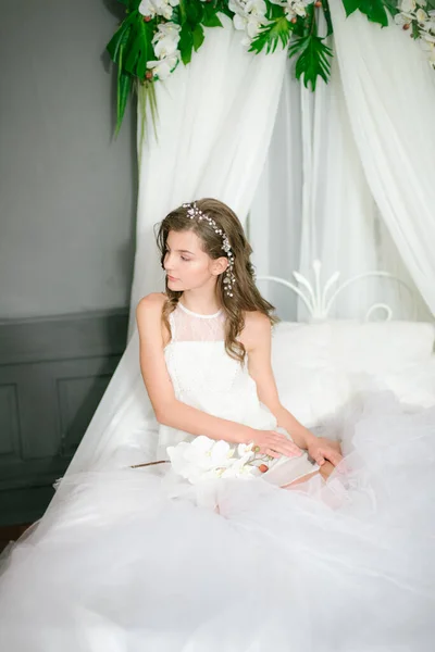 迷人的小女孩穿着浪漫的白色衣服 头戴天篷 手里拿着白色的兰花 躺在白色的空气床上 美与时尚 — 图库照片