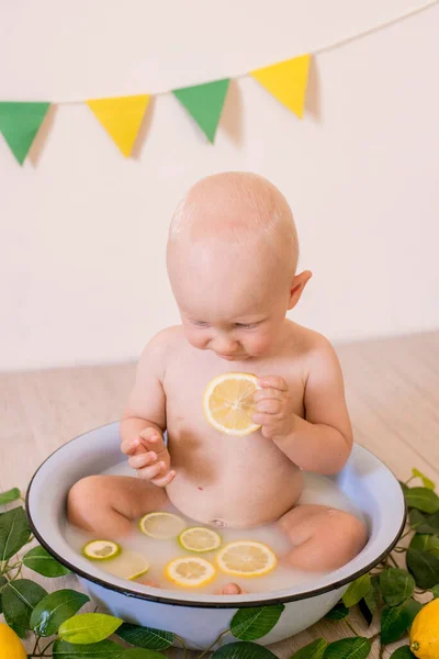 明るいスタジオでミルクとレモンと流域に座って金髪の髪を持つかわいい幼児の男の子 健康な子供時代 — ストック写真