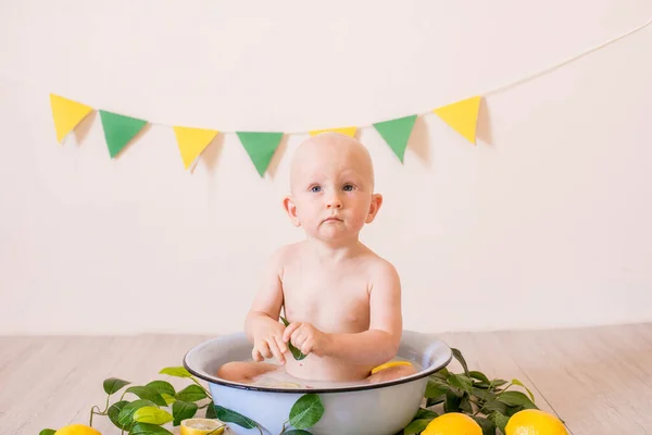 可爱的蹒跚学步的男孩 金发碧眼坐在一个装有牛奶和柠檬的水池里 在一个明亮的工作室里 健康的童年 — 图库照片