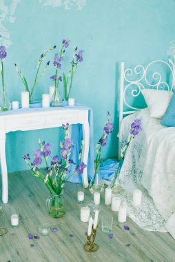 Yatak odasının içi havadar yatak odası ve bahar mavisi süsen çiçekleri ve mumlarla süslenmiş mavi duvar. Gelinin Yatak Odası