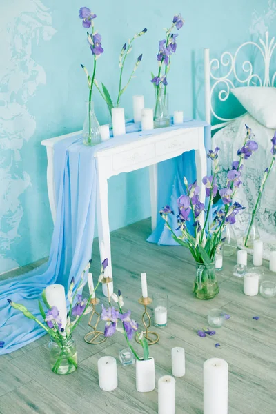 卧室内部有通风床和蓝色墙壁 装饰着春天的蓝色虹膜和蜡烛 新娘的Boudoir — 图库照片