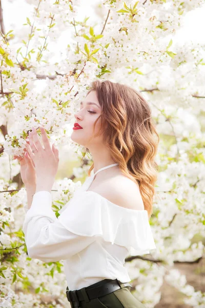 晴れた日に開花桜の庭で春に白いロマンチックなシルクのブラウスで素敵な若い女の子 春とファッション — ストック写真