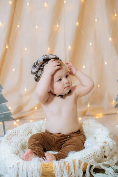 サスペンダー 蝶ネクタイの小さなかわいい子供は 針とクリスマスボールで飾られたバスケットに座っています お祭り気分 メリークリスマス — ストック写真