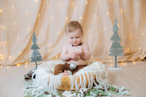 Malé Roztomilé Dítě Kšandách Motýlek Sedí Košíku Zdobeném Jehlami Vánočními — Stock fotografie
