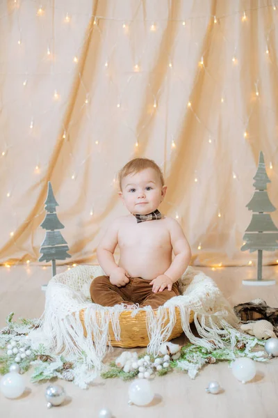 Malé Roztomilé Dítě Kšandách Motýlek Sedí Košíku Zdobeném Jehlami Vánočními — Stock fotografie