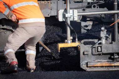 Yolda asfalt sıkıştıran tekerlekli bir işçi