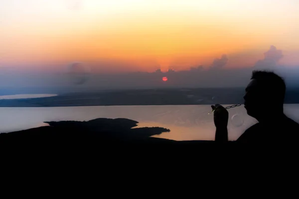 Silhouette Eines Mannes Der Seifenblasen Über Den Orangefarbenen Himmel Pustet — Stockfoto