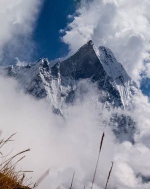Nepal 'de güneşli bir günde bulutların içinde karlı zirveleri olan Manaslu dağı.