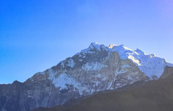 Snötäckt berg med blå himmel, moln och dimma — Stockfoto