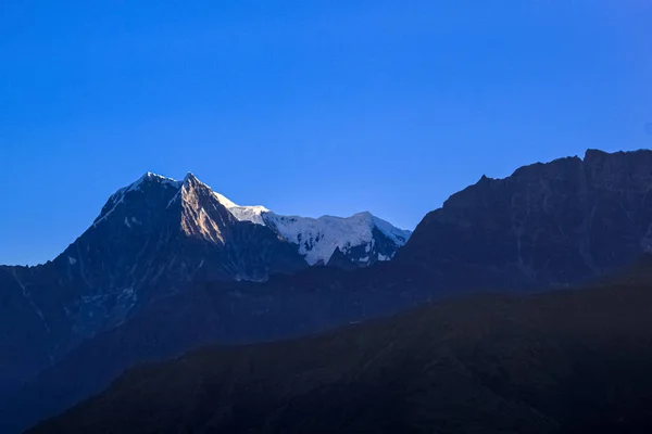 Met sneeuw bedekte berg met blauwe lucht, wolken en mist — Stockfoto