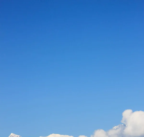 Pokryta śniegiem góra z błękitnym niebem, chmurą i mgłą — Zdjęcie stockowe