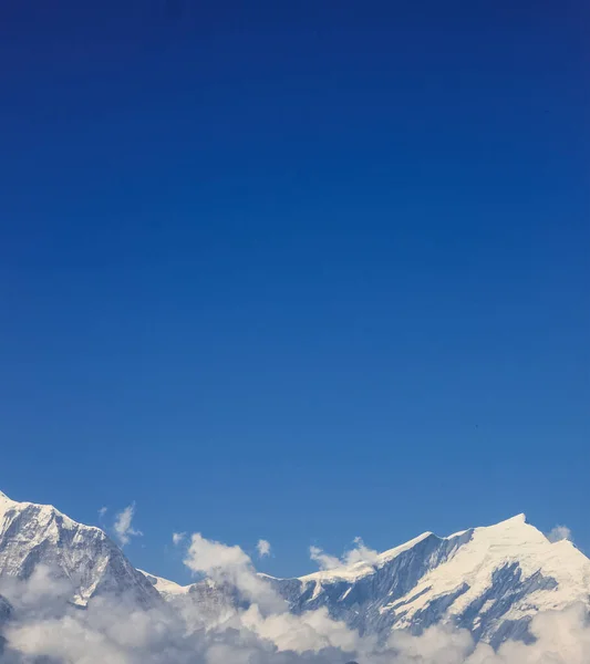Sněhem pokrytá hora s modrou oblohou, mrakem a mlhou — Stock fotografie