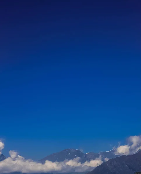 青空と雲と霧に覆われた雪に覆われた山 — ストック写真