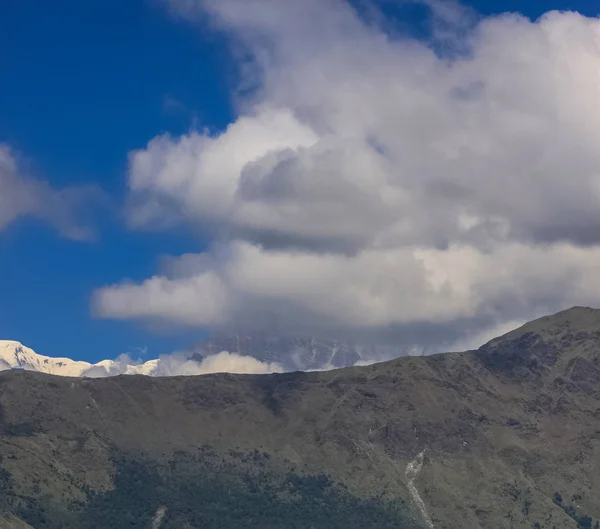 Snötäckt berg med blå himmel, moln och dimma — Stockfoto