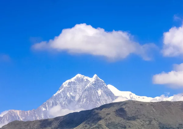 Met sneeuw bedekte berg met blauwe lucht, wolken en mist — Stockfoto