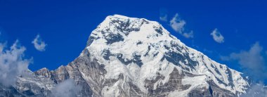 Tepenin tepesinde, kar ve beyaz bulutlarla kaplı.