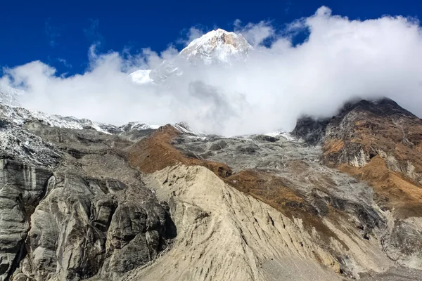 Parte superior de la colina, cubierta de nieve y nubes blancas — Foto de Stock