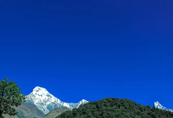 Tepenin tepesinde, kar ve beyaz bulutlarla kaplı. — Stok fotoğraf