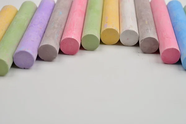 Pedaços de giz em uma variedade de cores dispostas em linha em um wh — Fotografia de Stock