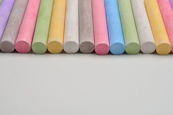 Pedaços de giz em uma variedade de cores dispostas em linha em um wh — Fotografia de Stock