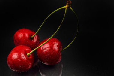 Su ile üç kırmızı kiraz düşünceye karşı yansıtıcı siyah bac