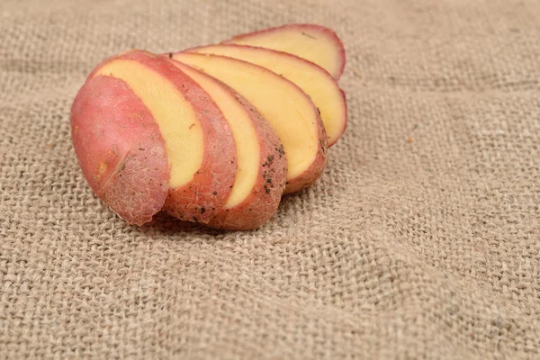 New fresh red potatoes cute in slices on jute background. Concep — Stock Photo, Image