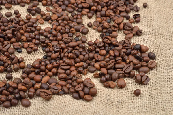 Granos de café sobre fondo de yute marrón —  Fotos de Stock