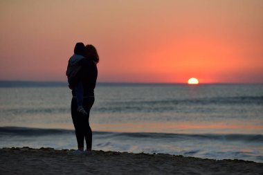 Anne ve oğlu sahilde günbatımı zaman ayakta. Sağlıklı