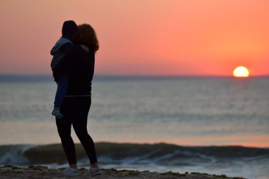 Anne ve oğlu sahilde günbatımı zaman ayakta. Sağlıklı